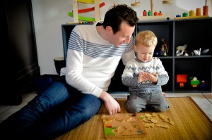 arthur regarde une piece du puzzle sous le regard de son papa